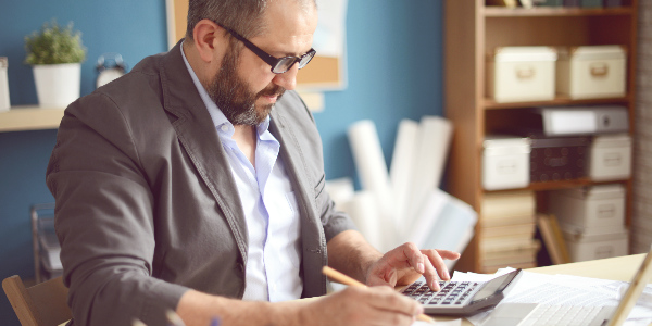 a male office manager works through group insurance plans information to calculate if his company is getting the best deal