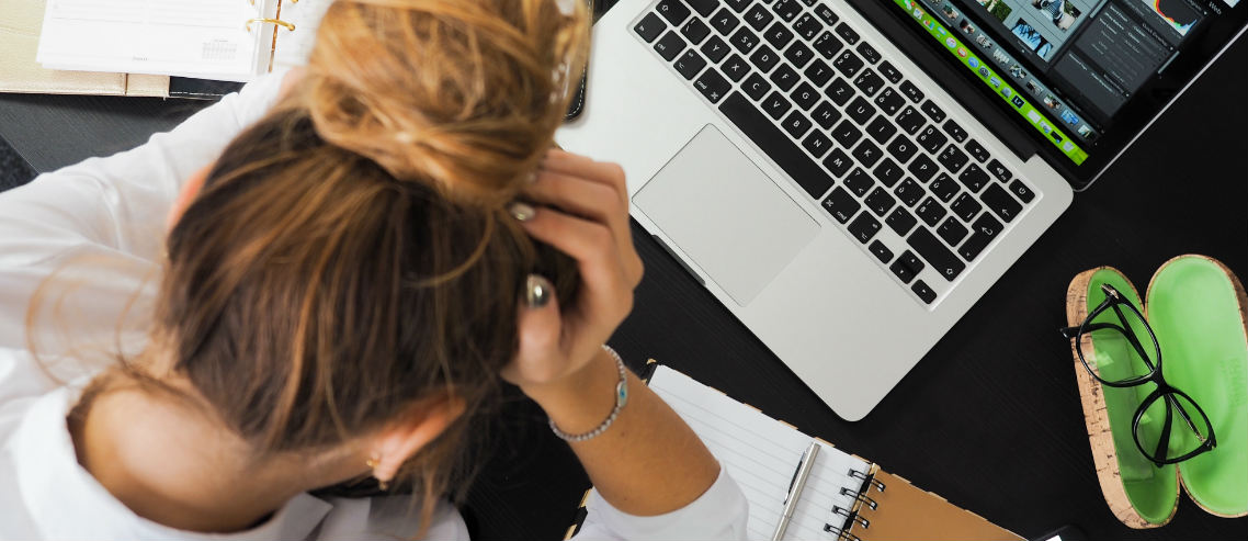 a woman sits at her desk with her head in her hands portraying the need to be conscious of your own mental health in hong kong, and knowing how to cope with stress and anxiety