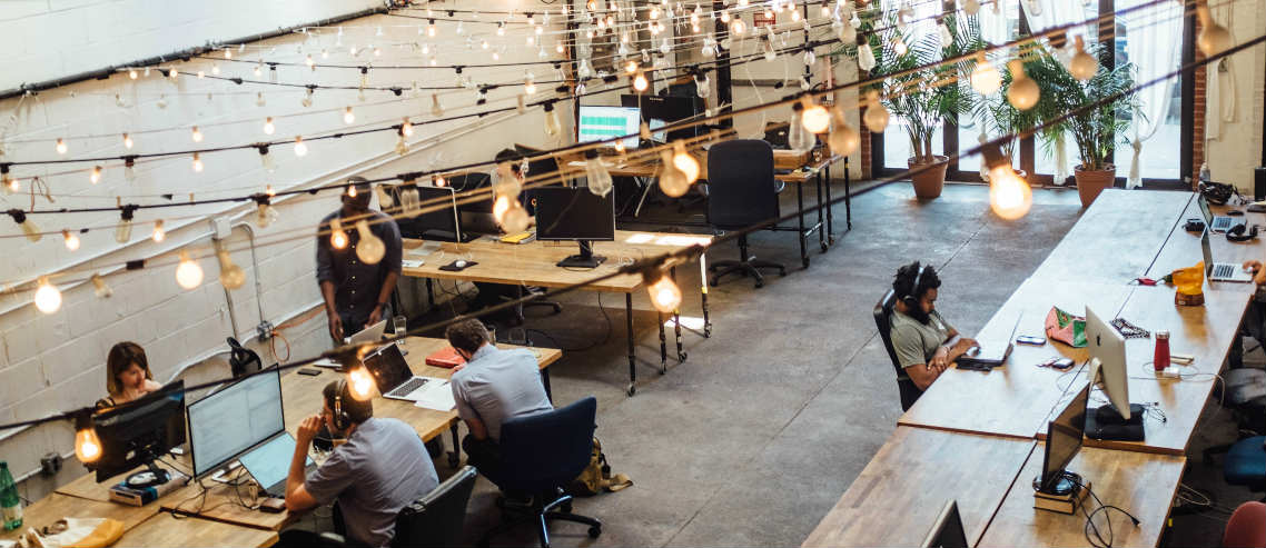 a group of employees work collaboratively in an diverse and modern workspace, outlining the importance of understanding what types of employee health benefits might be useful in today's working environment